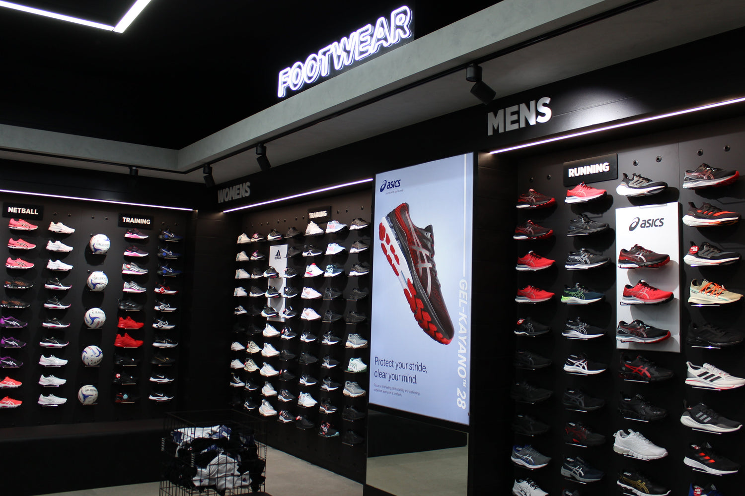 Shoe display area with 'Footwear' and 'Mens' signs in a store.