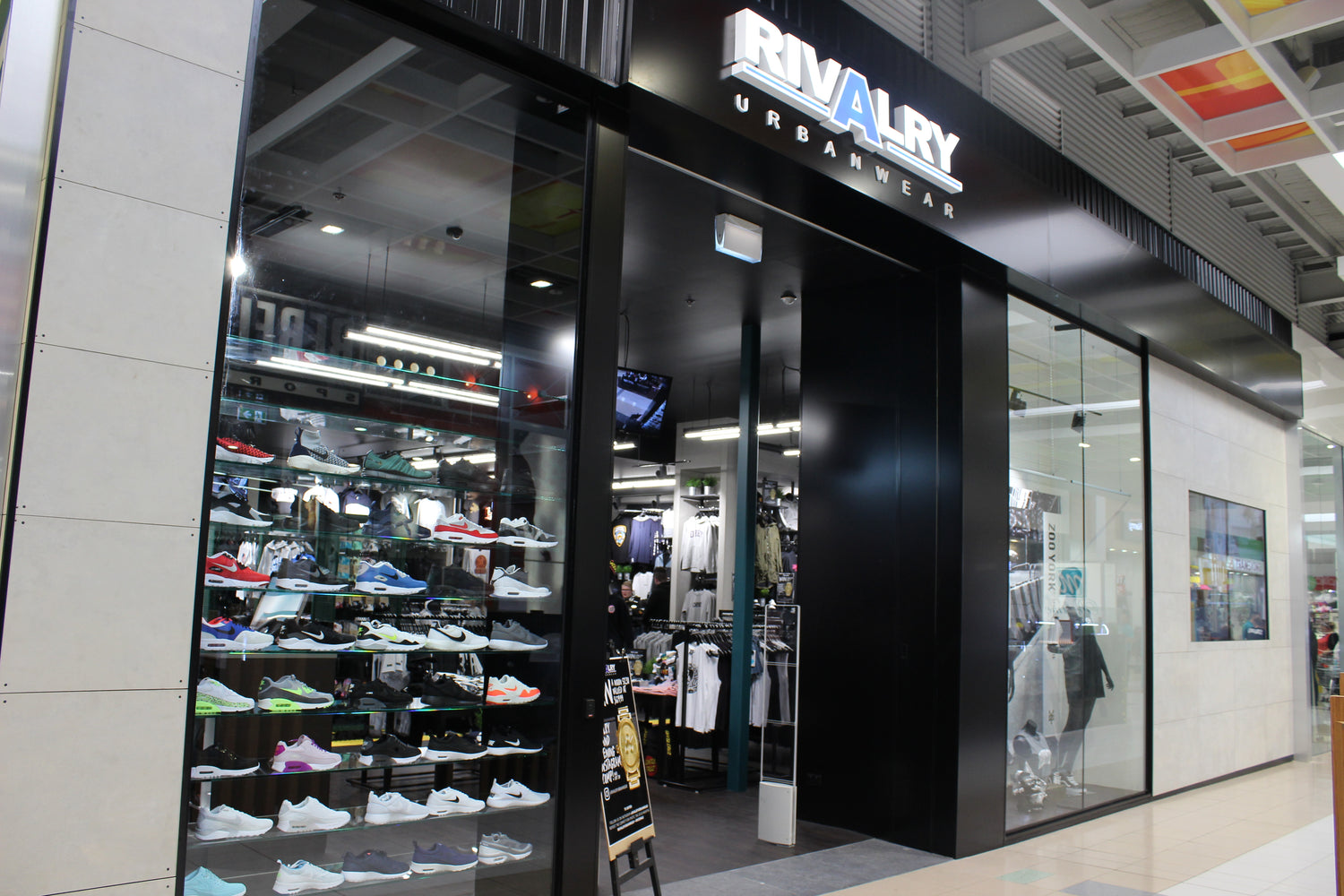 Rivalry Urbanwear store entrance with glass doors and visible shoe display inside.